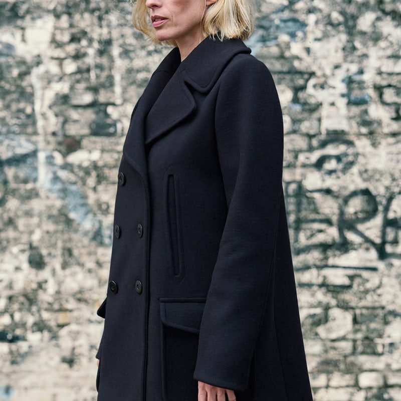 Frau mit Jacke Loki vor Steinmauer